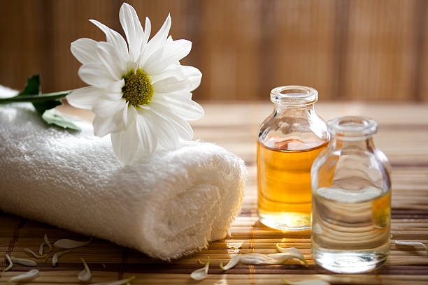 Premium amber wellness oils with white flower and rolled towel